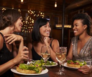 Three female friends eating dinner together at a restaurant